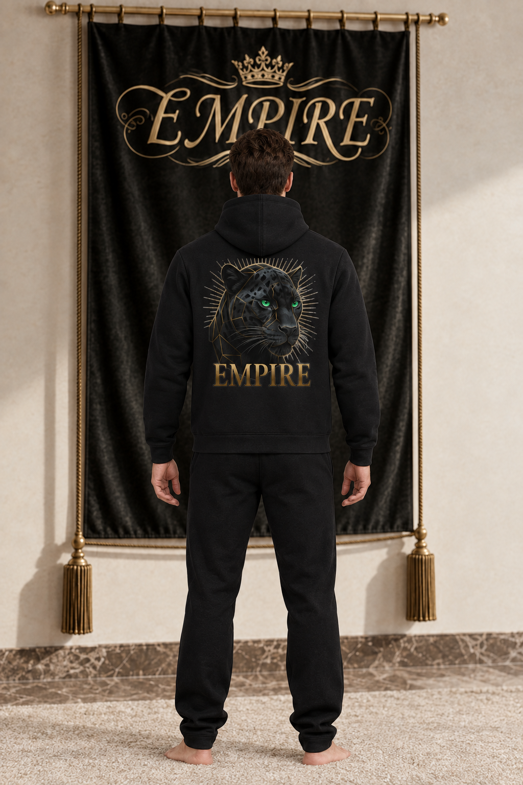 Black men's EMPIRE high-neck zip-up hoodie with emerald-eyed panther and gold ray back graphic, rear view on barefoot male model