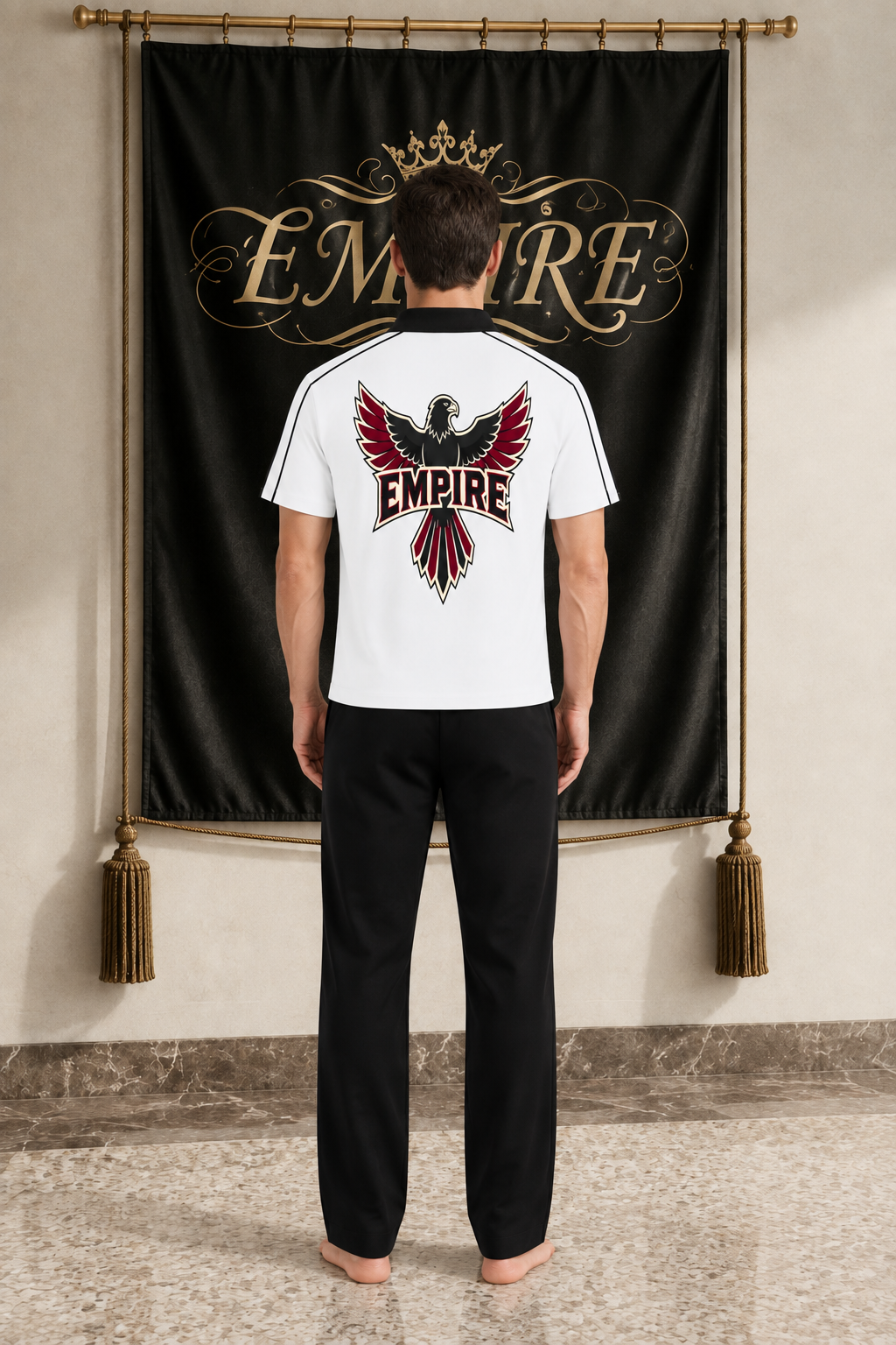 White men's EMPIRE contrast-collar polo shirt with black and burgundy spread-wing falcon back graphic, rear view on barefoot male model
