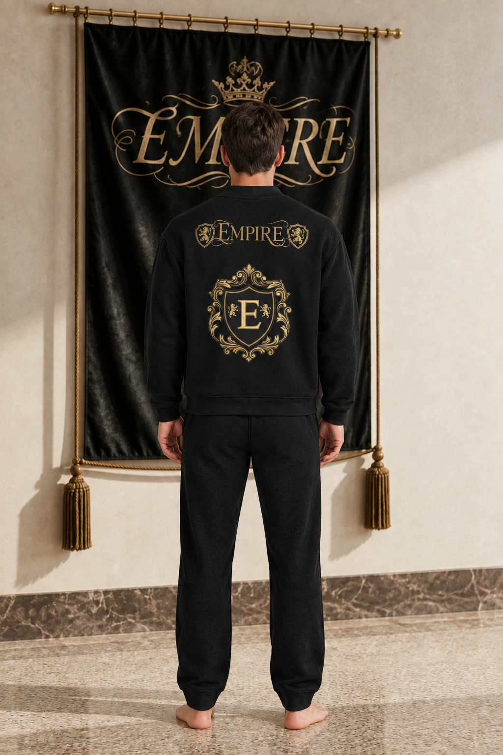 Black men's EMPIRE fleece button cardigan with gold heraldic wordmark and ornate crest on the back, rear view on barefoot male model