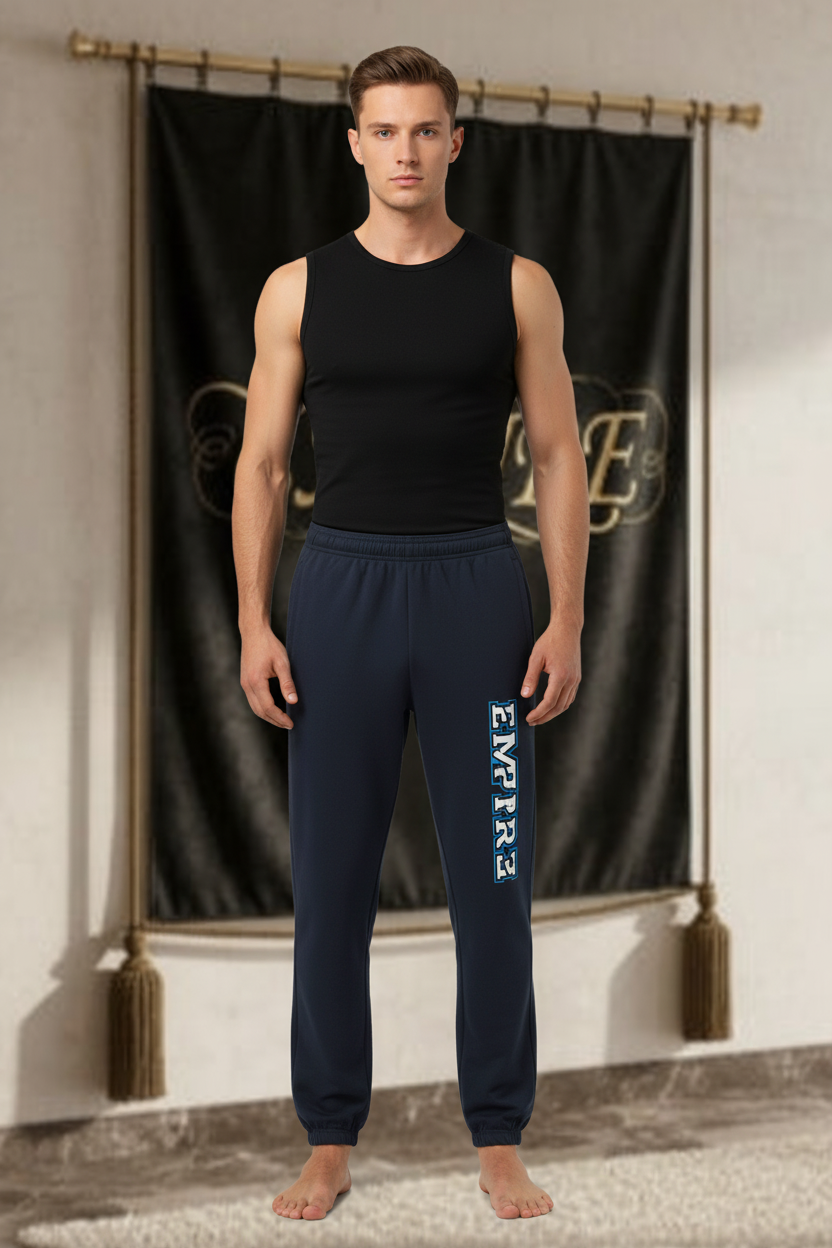 Homme portant le jogger EMPIRE Essential bleu marine foncé avec marquage vertical EMPIRE blanc bordé de bleu sur la jambe, vue de face.