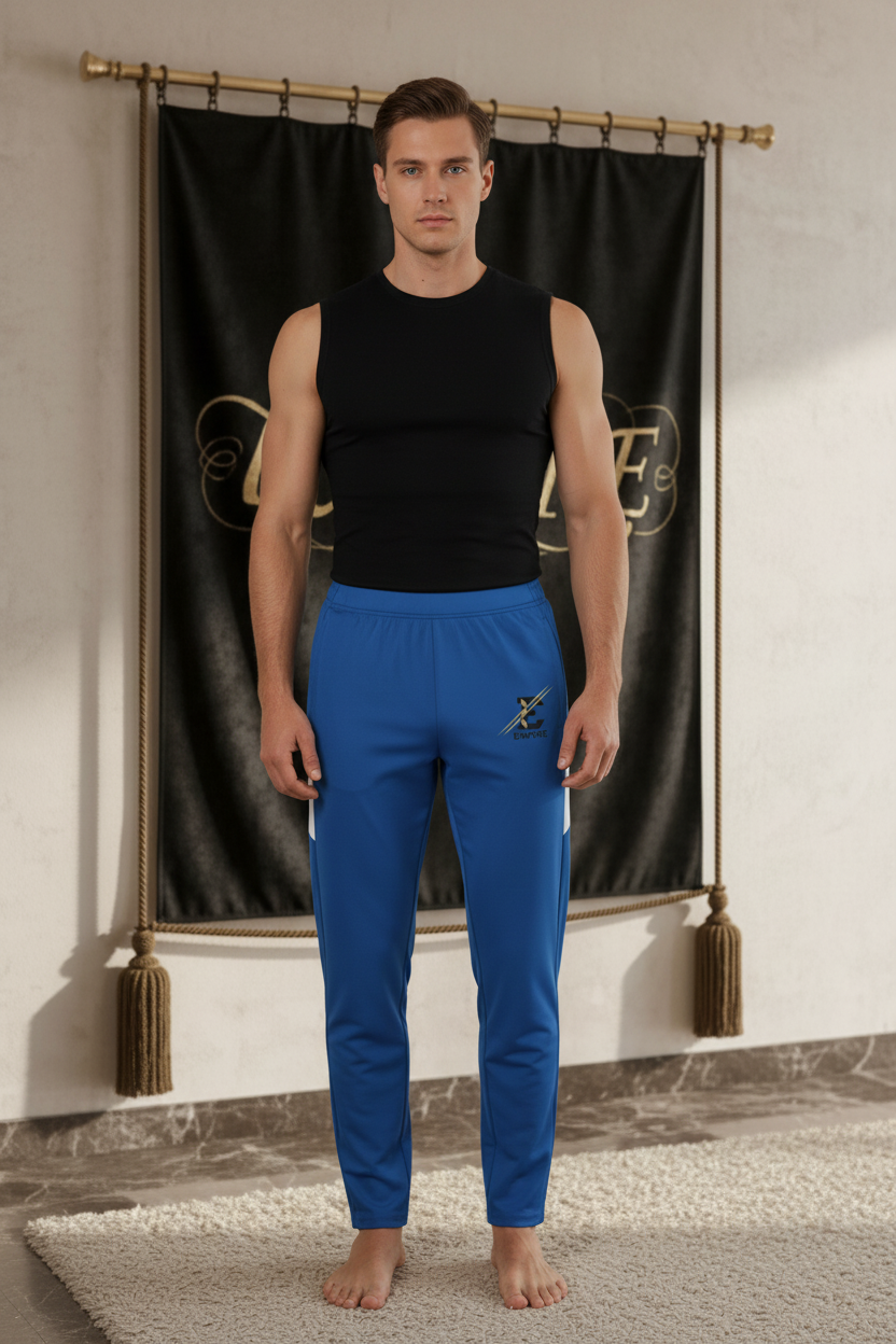 Homme portant le pantalon EMPIRE Rail Mark bleu royal fuselé avec panneaux blancs et emblème noir et doré, sans cordon visible, vue de face.