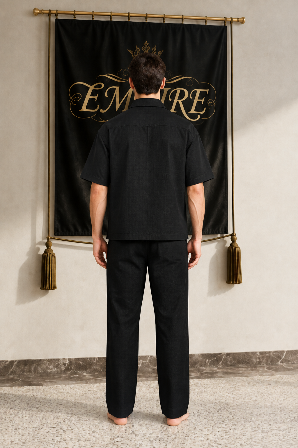 Black men's EMPIRE boxy short-sleeve button shirt with a plain back, rear view on barefoot male model