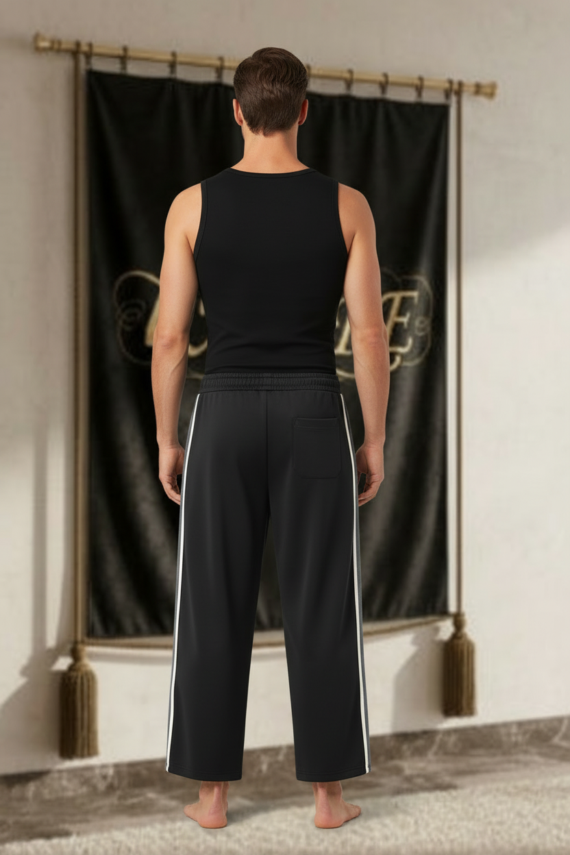 Homme portant un pantalon EMPIRE noir à bandes latérales blanches avec une poche arrière discrète, sans logo au dos, vue arrière.