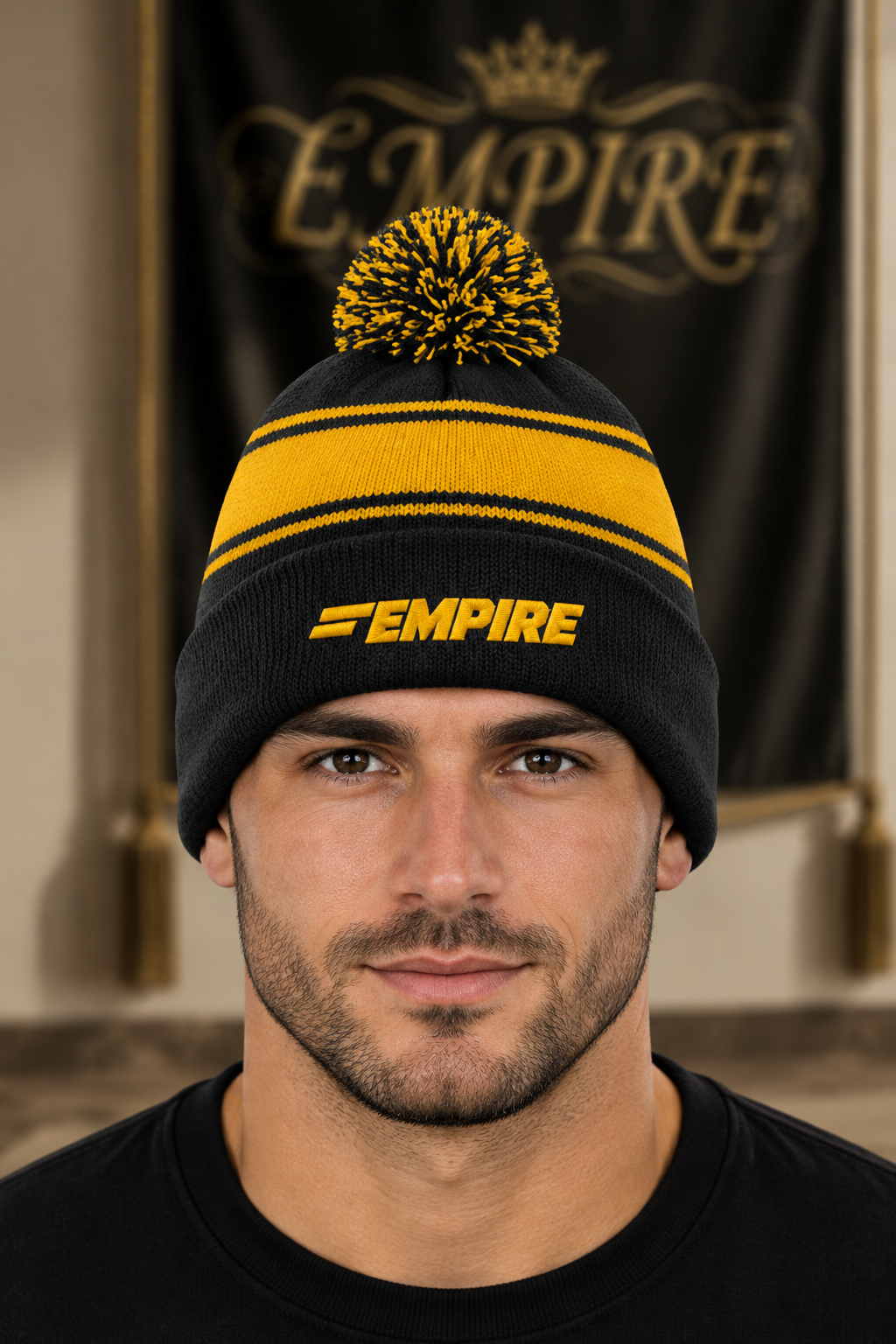 Bonnet homme EMPIRE noir et jaune à rayures, pompon bicolore et logo brodé jaune sur le revers, porté en gros plan dans le décor EMPIRE