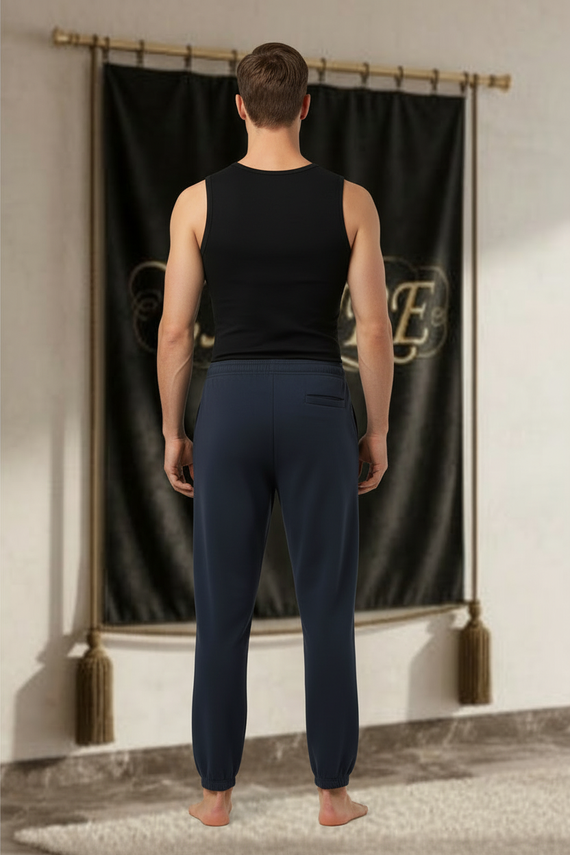 Homme portant le jogger EMPIRE Essential bleu marine foncé, uni au dos avec chevilles élastiquées, vue arrière.