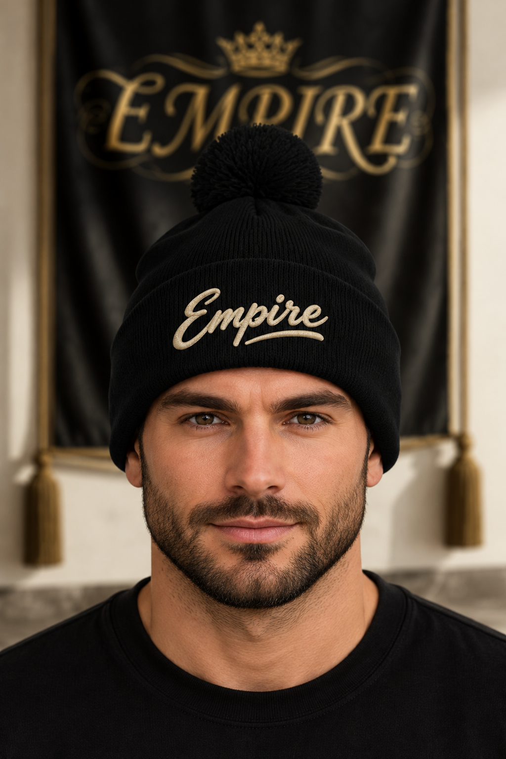 Bonnet noir à pompon homme EMPIRE, signature Empire brodée claire sur le revers, porté en gros plan dans le décor EMPIRE