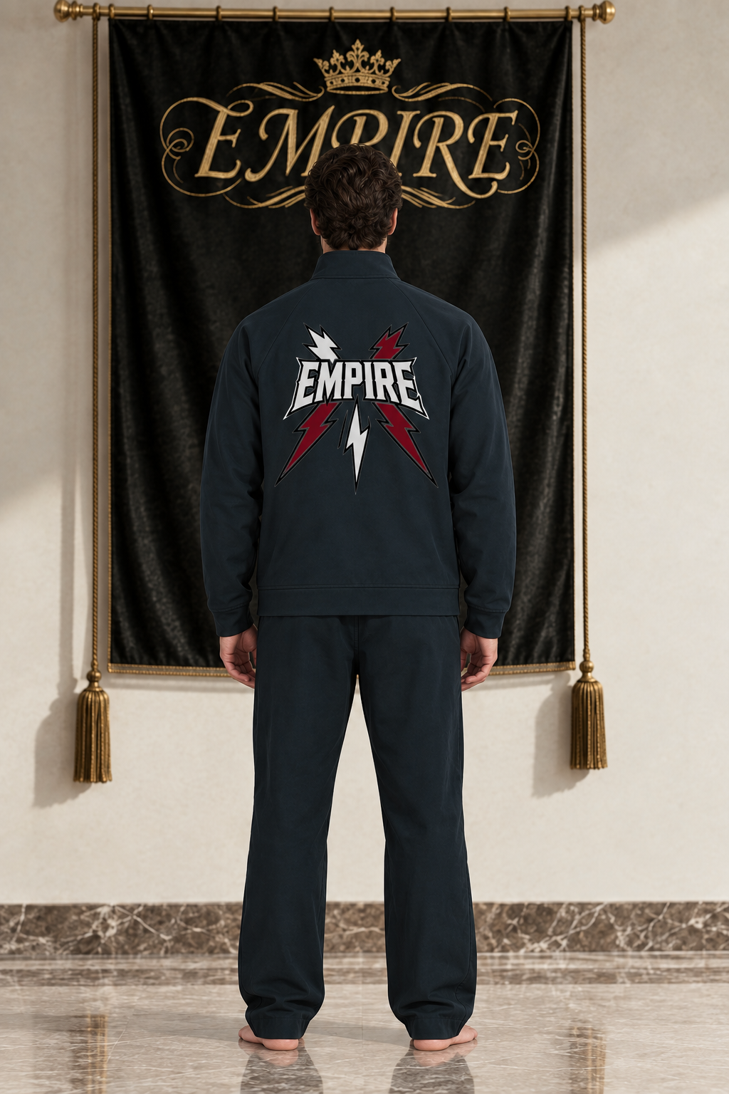 Dark men's EMPIRE stand-collar raglan track jacket with large white wordmark and five lightning bolts, rear view on barefoot male model
