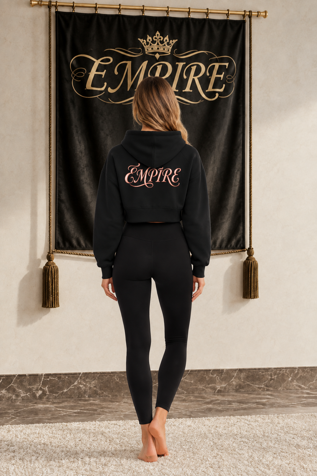 Black women's EMPIRE cropped zip-through hoodie with metallic rose-pink script wordmark on the upper back, rear view