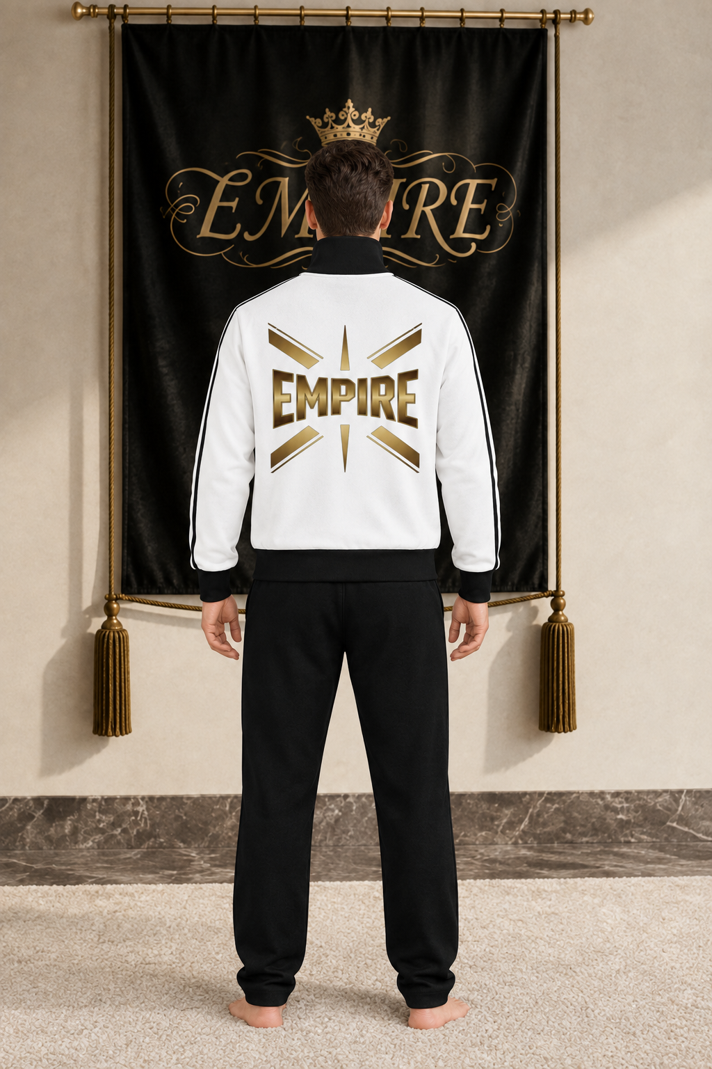 White men's EMPIRE fleece track jacket with black trims and large gold radiating back wordmark, rear view on barefoot male model