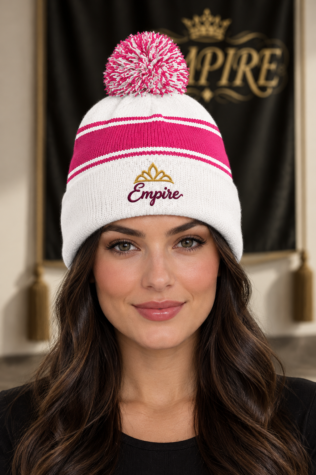 Bonnet femme EMPIRE blanc et rose à rayures, pompon bicolore, signature bordeaux et diadème doré brodés, porté en gros plan dans le décor EMPIRE